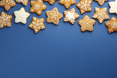 Tasty star shaped Christmas cookies with icing on blue background, flat lay. Space for textの写真素材