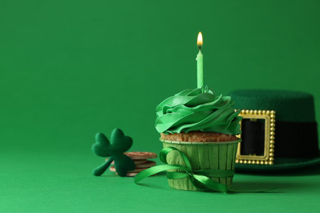 St. Patrick's day party. Tasty cupcake with burning candle and leprechaun hat on green backgroundの写真素材