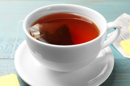 Tea bag in cup with hot drink on light blue wooden table, closeupの写真素材
