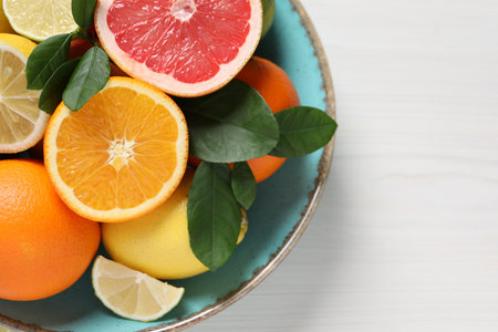 Different cut and whole citrus fruits on white wooden table, top view. Space for textの写真素材