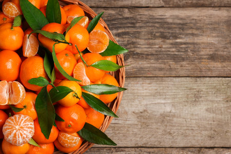 Fresh ripe juicy tangerines and green leaves on wooden table, top view. Space for textの写真素材
