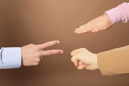 People playing rock, paper and scissors on brown background, closeup
