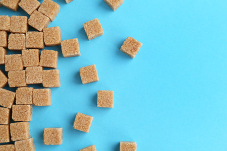 Brown sugar cubes on light blue background, top view. Space for textの写真素材