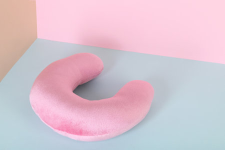 Pink travel pillow on color background, space for text