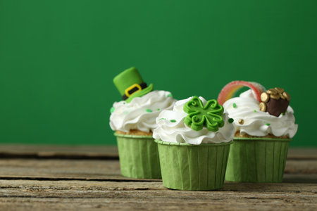 St. Patrick's day party. Tasty festively decorated cupcakes on wooden table, closeup. Space for textの写真素材