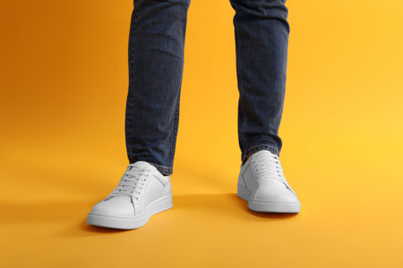 Man wearing stylish white sneakers on yellow background, closeupの写真素材