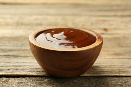 Tasty barbeque sauce in bowl on wooden table, closeupの写真素材