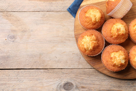 Delicious sweet muffins on wooden table, top view. Space for text