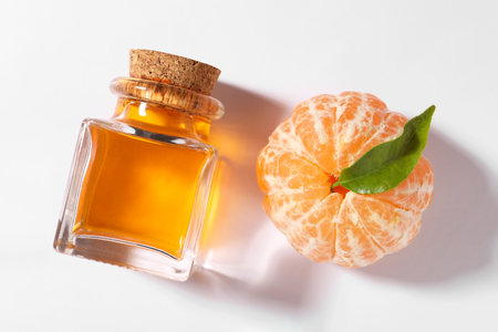 Aromatic tangerine essential oil in bottle and citrus fruit on white table, top viewの写真素材