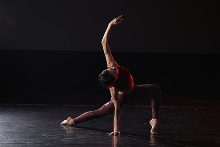Young woman performing acrobatic element on stage indoors