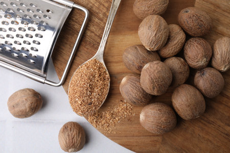 Spoon with grated nutmeg, seeds and grater on white table, flat layの写真素材