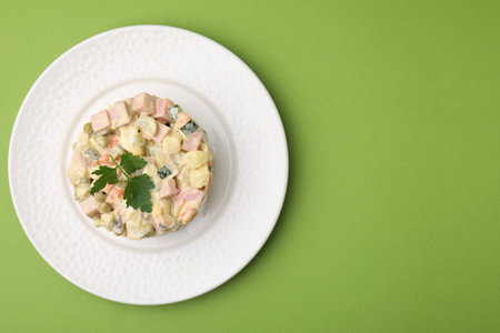 Tasty Olivier salad with boiled sausage on green table, top view. Space for textの写真素材