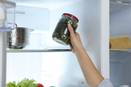 Young woman taking jar of pickles out of refrigerator, closeupの写真素材