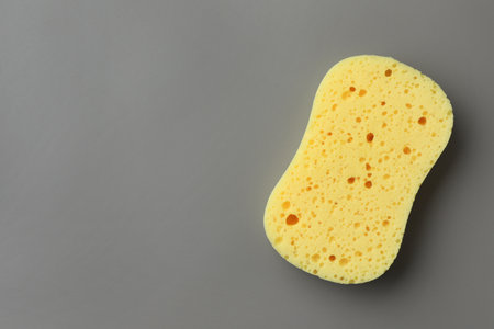 New yellow sponge on gray background, top view. Space for textの写真素材