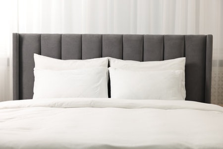 Soft white pillows and duvet on bed at homeの写真素材