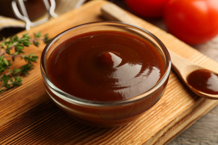 Tasty barbeque sauce in bowl and spoon on table, closeupの写真素材