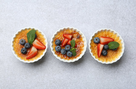 Delicious creme brulee with berries and mint in bowl on gray textured table, top viewの写真素材