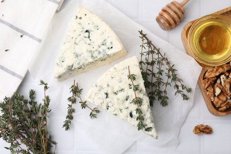 Tasty blue cheese with thyme, walnuts and honey on white tiled table, flat layの写真素材