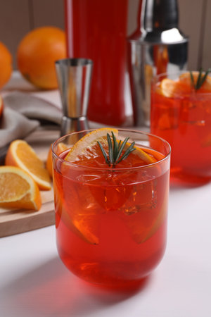 Aperol spritz cocktail, ice cubes, rosemary and orange slices in glass on white wooden table, closeupの写真素材