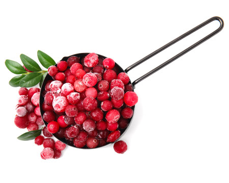 Frozen red cranberries in scoop and green leaves isolated on white, top viewの写真素材