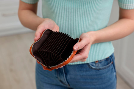 Woman with empty wallet at home, closeup