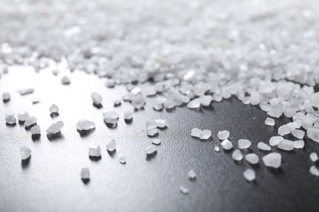 Scattered white natural salt on black table, closeupの写真素材
