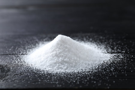 Pile of organic salt on black wooden table, closeupの写真素材
