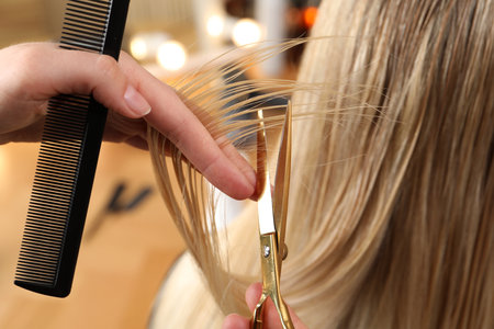 Hairdresser cutting client's hair with scissors in salon, closeupの写真素材