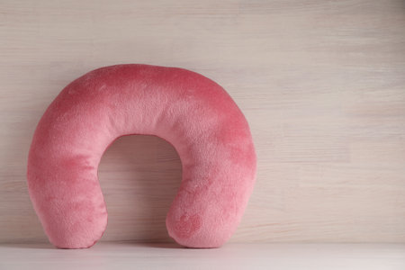 Pink travel pillow on light wooden background, space for textの写真素材