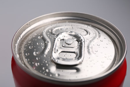 Energy drink in wet can on light gray background, closeup