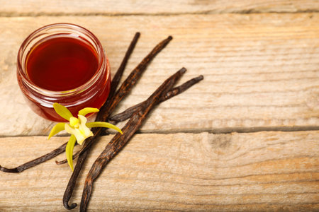 Aromatic vanilla extract, pods and flower on wooden table, above view. Space for textの写真素材