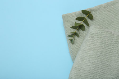 Terry towels and eucalyptus branch on light blue background, top view. Space for textの写真素材