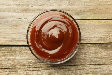 Tasty barbeque sauce in bowl on wooden table, top viewの写真素材