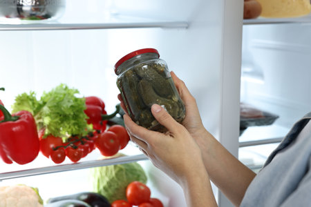 Young woman taking jar of pickles out of refrigerator, closeupの写真素材