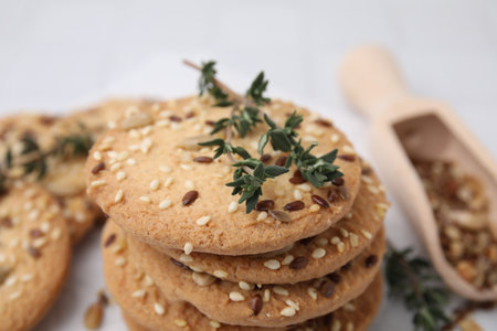 Stack of cereal crackers with flax, sesame seeds and thyme on blurred background, closeupの写真素材