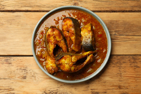 Tasty fish curry on wooden table, top view. Indian cuisine