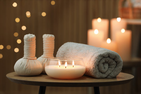 Spa composition. Herbal bags, towel and burning candle on wooden tableの写真素材