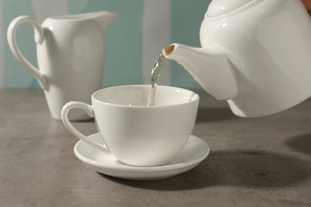 Pouring aromatic tea in cup at gray table, closeupの写真素材