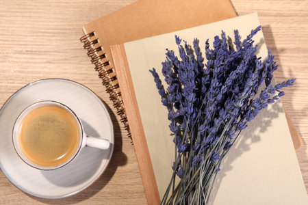 Bouquet of beautiful preserved lavender flowers, notebooks and cup of coffee on wooden table, flat layの写真素材