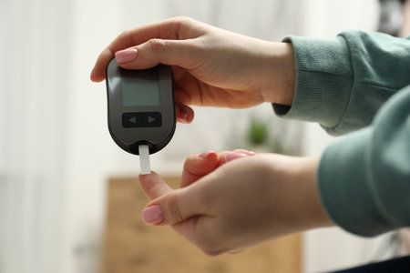 Diabetes. Woman checking blood sugar level with glucometer at home, closeupの写真素材