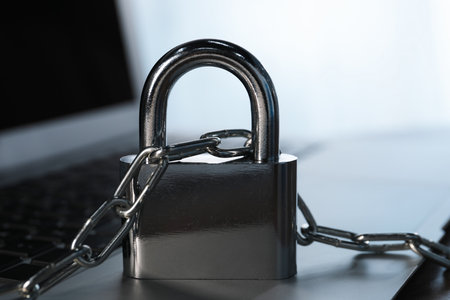 Cyber security. Laptop with padlock and chain on table, closeup