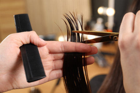 Hairdresser cutting client's hair with scissors in salon, closeupの写真素材