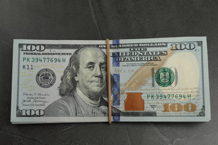 Money exchange. Dollar banknotes on dark gray textured background, top view