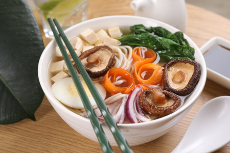 Delicious vegetarian ramen served on wooden table, closeup. Noodle soup
