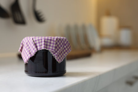 Jar of jam covered with beeswax food wrap on white table indoors, space for textの写真素材