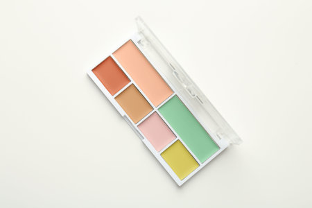 Colorful correcting concealer palette on white background, top view