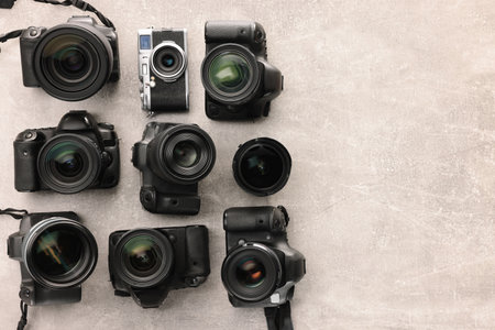 Modern cameras on gray textured table, flat lay. Space for textの写真素材