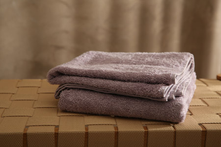 Soft terry towels on wicker bench indoors, closeupの写真素材