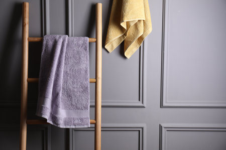 Soft terry towels and wooden ladder indoors, space for textの写真素材