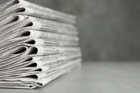 Stack of newspapers on light gray stone table, closeup with space for text. Journalist's workの写真素材